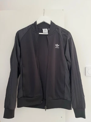  Adidas jacka/tröja - Säljer en svart Adidas jacka/tröja. Bra kvalite, dubbel zip samt fickor med dragkedjor. Nypris ca 800kr. Hör gärna av er vid frågor!