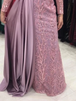 Lång rosa klänning med spets och släp - Elegant långklänning i ljusrosa med glittriga broderier och spetsdetaljer. Klänningen har ett dramatiskt släp i satin och långa ärmar. Perfekt för speciella tillfällen och bal.