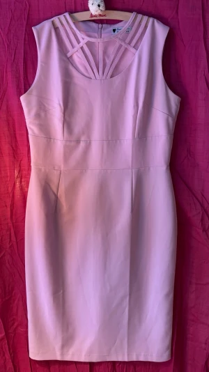 Ljusrosa retroklänning från Daisy Dapper - Snygg ljusrosa pennklänning från Daisy Dapper med fina meshdetaljer och band upptill. Klänningen är ärmlös och går strax över knäna, slits baktill.  Perfekt sommarklänning för dig som gillar stilrena plagg med unika detaljer.