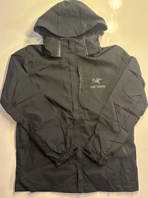 Svart Arc’teryx regnjacka L - Säljer denna Svarta arcteryx regnjackan i storlek L, men kan troligtvis passa en M. Vattentät som ni kan se i bilden! Har även en M men kan nog också passa en stor S (kolla profilen) Säljer även massa annat!