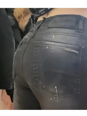 Svarta skinny jeans från Dsquared2 - Snygga svarta skinny jeans från Dsquared2 köpt av en annan tjej en gång i tiden  med klassisk femficksmodell och diskret logga på bakfickan. Jeansen har en tight passform och coola färgstänk som ger en unik look. Perfekta för dig som vill sticka ut med stilrena detaljer. Går åt mötas upp i Helsingborg o Malmö annars tillkommer frakt kostnad .
