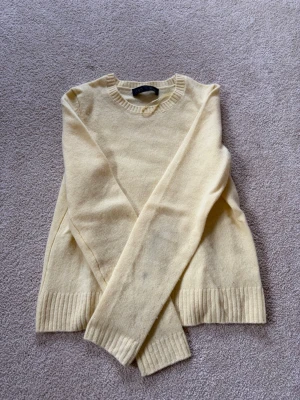 Ljusgul stickad tröja från Zara - Mysig ljusgul stickad tröja från Zara med rund halsringning och ribbade muddar vid ärmslut och nederkant. Tröjan har en enkel och stilren design som passar perfekt till många olika outfits. Materialet känns mjukt och bekvämt. Står S men är en XS