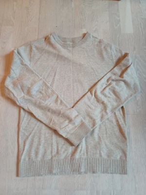 Beige stickad tröja med rund hals.Storlek s (Stor I storlek ) - En stilren beige stickad tröja med rund halsringning och ribbade muddar vid ärmslut och nederkant. Perfekt för lager-på-lager och enkel att matcha med olika outfits.