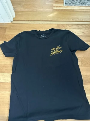 Svart The Voice of the Heroes t-shirt - Säljer en svart t-shirt från The Voice of the Heroes med gul text på bröstet. Klassisk passform med rund hals och korta ärmar. Perfekt för dig som gillar streetwear och vill ha en stilren men ändå unik look.