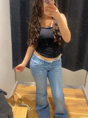 Ljusblå bootcut jeans med rå kant - Säljer ett par ljusblå bootcut jeans med snygg rå kant upptill. Jeansen har klassisk femficksdesign och är tillverkade i denim med lätt stretch. Perfekta för en avslappnad och trendig look.