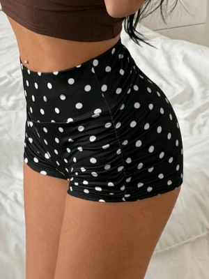 Svarta prickiga mid waist shorts - Snygga svarta shorts med vita prickar och mellan midja. De är tighta och har en stretchig passform som framhäver figuren. Perfekta för en trendig och sportig look. Materialet känns mjukt och följsamt mot huden. Använd max 1 gång. (Inte mina bilder, från shein) 