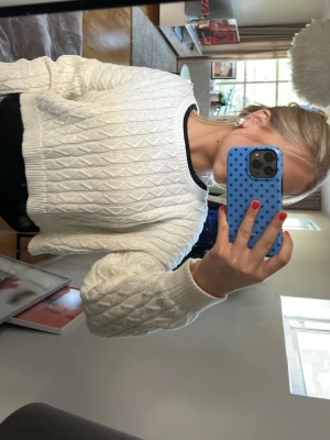 Vit kabelstickad cropped tröja - Säljer en vit kabelstickad tröja med croppad passform och rund halsringning, Perfekt för lager-på-lager och enkel att styla till jeans eller kjol.