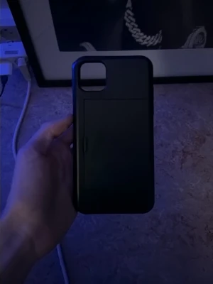 Svart mobilskal med kortfack - Snyggt svart mobilskal med ett praktiskt skjutbart kortfack på baksidan. Skalet är gjort i tålig plast och har en stilren, matt finish. Passar till mobil med stor kameraöppning i hörnet. Perfekt för dig som vill ha både skydd och plats för kort.