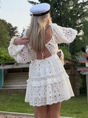 Vit klänning - Superfin vit kortklänning med broderi.  Öppen i ryggen och har vida trekvartsärmar. Perfekt till studenten 