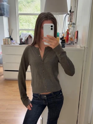  cardigan med knappar - Snygg cardigan med rund halsringning och knäppning framtill. Tröjan har långa ärmar och ribbade muddar vid ärmslut och nederkant. Perfekt att slänga över en topp eller bära stängd för en clean look.