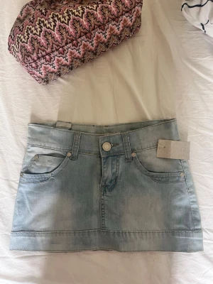 Ljusblå jeanskjol från Smiff💗 - Ljusblå jeanskjol från Smiff med klassisk femficksdesign och snygga hjärtformade bakfickor. Kjolen har knapp och dragkedja framtill samt bälteshällor. Perfekt för dig som gillar denim och vill ha en kort kjol med coola detaljer. ✨✨💗