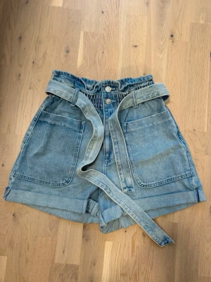Jeansshorts från Zara  - Snygga jeansshorts i ljusblå denim. Shortsen har stora fickor fram och bak samt ett matchande denimskärp i midjan. Perfekta för en avslappnad och trendig look. Söta med en vit topp 🤍
