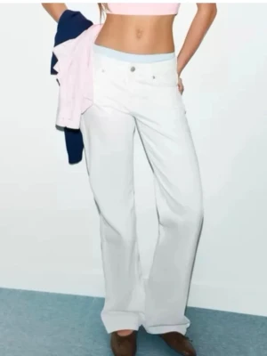 Vita jeans zara - Säljer ett par snygga vita jeans från Zara med rak och vid passform. Jeansen har klassisk femficksdesign, hällor i midjan och stängs med knapp och dragkedja. Perfekta för en trendig och avslappnad look.