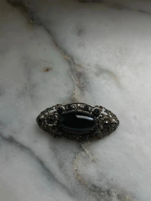 Blå brosch - Silvrig brosch med marinblå sten, ca 5,5 x 2 cm, mycket bra skick.