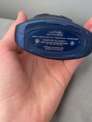 Layton parfym från Parfums de Marly - Exklusiv parfymflaska i mörkblått glas med silverdetaljer från Parfums de Marly. Doften heter Layton och flaskan har en elegant, robust form med metallisk sköld på korken. Tillverkad i Frankrike