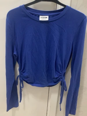 Blå långärmad topp  - Snygg blå kroppad långärmad topp från vero moda i storlek XS med knyttningar på båda sidor. Mjukt och stretchigt material med rund halsringning och figurnära passform i midjan. Är i mycket bra skick💙