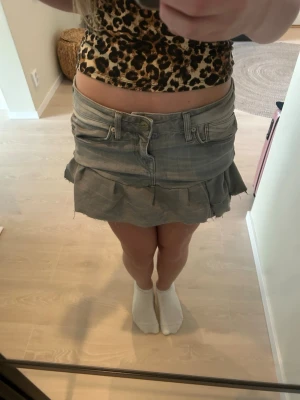 Grå jeanskjol med volangkant - Säljer en kort grå jeanskjol med volangkant och råa kanter. Kjolen har klassiska jeansdetaljer som fickor och bälteshällor. Perfekt för dig som gillar en edgy och trendig stil. FINNS SKAVANKER. Har sytt den själv så det finns vissa små hål och trådar som hänger ut, skulle behövas sy om. Billigt pris pga detta