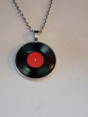Halsband med vinylskive-hänge - Unikt halsband med ett runt hänge LP-SKIVA I 2D Retro mode. Kedjan är i silverfärgad metall och hänget har en cool retrostil, perfekt för dig som älskar musik och vintagevibbar.