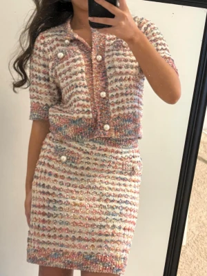 Helt nytt Urban Revivo set -   Superfint tvådelat set i tweed/bouclé med pärlknappar och skimriga detaljer. Består av kortärmad cardigan/jacka och matchande kjol. Chanel-inspired stil 💖 • Helt oanvänt • Storlek L (EU 40) • Säljs som set • Nypris: 2000 kr  Perfekt till fest, brunch eller en classy vardagslook ✨