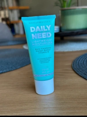 Daily Need Lightweight Moisturizer - Lätt ansiktskräm från Makeup Mekka med SPF 30. Innehåller betakaroten, mangosmör och vitamin E. Kommer i en turkos tub på 30 ml med vit kork. Perfekt för daglig återfuktning och skydd mot solen.