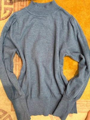  stickad tröja  - Mysig blå stickad tröja från KappAhl med hög krage, samt lätt puffade axlar för en trendig look.