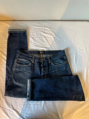 Mörkblå selvedge jeans - Snygga mörkblå jeans från Neuw med klassisk femficksdesign och raka ben. Jeansen har kontrastsömmar och knappgylf. Perfekta för dig som gillar en stilren och tidlös look. Materialet är denim i bomull.