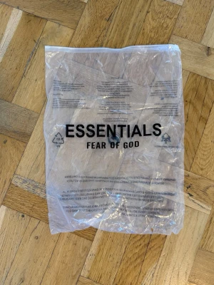 Grå hoodie från Fear of God Essentials - Snygg grå hoodie från Fear of God Essentials. Klassisk modell med huva och lång ärm, tillverkad i mjukt material. Perfekt för en avslappnad och trendig stil.