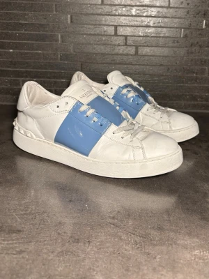 Valentino vita sneakers med blå detalj - Snygga och klassiska valentino open skor i bra skick, storlek 39 sitter 39-40. Finns lite repor osv som kommer med normalt använde givetvis äkta.