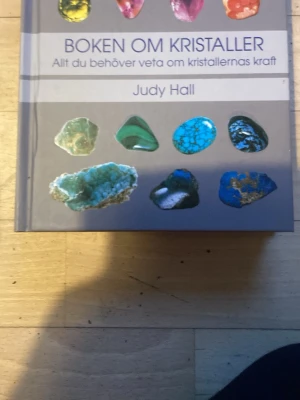 Boken om kristaller av Judy Hall - En inspirerande bok om kristaller av Judy Hall. Omslaget är grått med färgglada bilder på olika kristaller. Perfekt för dig som vill lära dig mer om kristallernas kraft och egenskaper. Inbunden och utgiven av Tukan förlag.