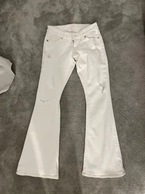 Vita utsvängda low rise jeans - Jättesnygga vita flare jeans från Gina Tricot teen14+. Aldrig använda bara testade.  OBS‼️‼️ de är uppsydda av sömmerska och innebenslängden nu är: 78cm. Det är den normala storleken.