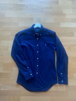 Ralph Lauren Skjorta - Snygg marinblå skjorta från Ralph Lauren i slim fit. Skjortan är i mycket bra skick och endast använd ett par gånger. Det är bara att fråga ifall du undrar över något!💫🙌🏻