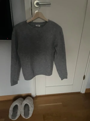Grå stickad tröja i ullmix - Mysig grå stickad tröja med rund hals och långa ärmar. Tröjan har en enkel, klassisk design och är tillverkad i en mjuk ullmix som håller dig varm under kyliga dagar. Perfekt att matcha med jeans eller kjol för en avslappnad look. Egentligen storlek 158/164 men passar en xs. Ganska nopprig.