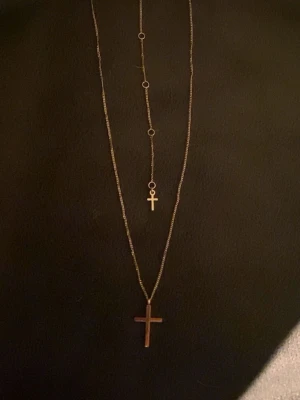 Guldigt halsband med två kors - Snyggt guldigt halsband med två korshängen i olika storlekar. Kedjan är tunn och har små runda detaljer längs med. Perfekt för dig som gillar lager på lager och vill ha en stilren accessoar med lite edge.