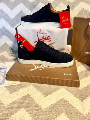 Christian Louboutin marinblå sneakers - Marinblå sneakers i mocka från Christian Louboutin med ikoniska röda sulor och blå nitar på tån. Lågt skaft, blå skosnören och vita gummisulor. Lyxig och edgy design som sticker ut. (Allt på bilderna medföljer)