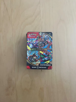 Pokémon Mega Evolution Booster Bundle - Pokémon Mega Evolution Booster Bundle med sex booster packs. Färgglad förpackning med motiv av olika Pokémon och texten 'Mega Evolution'. Perfekt för samlare eller dig som vill bygga din kortlek. Boxen är unsealed men packsen är oöppnade. (obs ej äkta). 