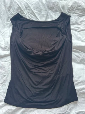 Svart draperad linnetopp - Svart ärmlös topp med snygg öppning på ryggen, perfekt till en lite mer casual look på en fest mm. 