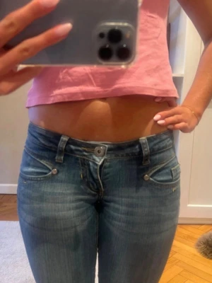Blå bootcut jeans med låg midja - Snygga blå bootcut jeans med låg midja och klassiska fem fickor. Jeansen har en lätt tvättad look och utsvängda ben.
