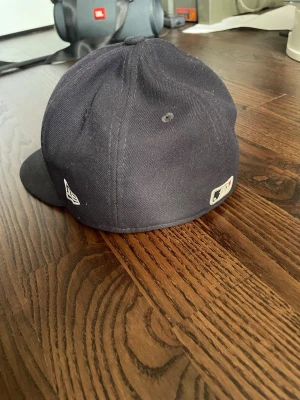 Boston Red Sox keps från New Era - Mörkblå basebollkeps från New Era med Boston Red Sox-logga broderad i rött och vitt framtill. Klassisk rak skärm och broderade ventilationshål. MLB-logga baktill och New Era-logga på sidan. Perfekt för dig som gillar sportig streetstyle.