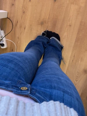 Blå bootcut jeans med råa kanter - Säljer ett par blå bootcut jeans med lite fransiga ändar. Dom är omsydda till g-rise. Jeansen har en snygg tvätt med lätt slitning på låren. Dom är lite långa i benen på mig som är 161 därav det fransiga ändarna. Förutom det är dom i bra skick och har inga andra synliga defekter. Köpte second hand för 300 kr.