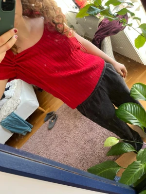Röd ribbad topp med snörning - Snygg röd ribbad topp med korta ärmar och snörningsdetaljer vid axlarna. Toppen har en rundad halsringning och är croppad i modellen. Perfekt att styla med jeans eller kjol för en trendig look. Knappt använd, står storlek 46-48 men passar mig som brukar ha S❤️