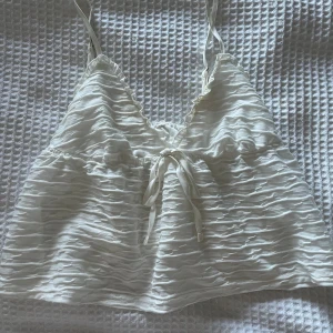 Vit linnetopp med knyt framtill - Supersöt vit linnetopp med tunna axelband och knyt framtill. Toppen har en lätt rynkad struktur i tyget. Perfekt för varma dagar och enkel att styla med jeans eller kjol. Perfekt till sommaren!💛Finns tyvärr ingen lapp kvar då den är bortklippt. Säljer då den blivit för liten. Toppen är i jättefint skick!💛Kan gå med på prisförslag vid snabb affär!! 