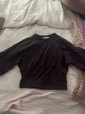 Vinröd långärmad croppad topp - En enkel och stilren vinröd långärmad topp med croppad passform. Tillverkad i mjukt material och har en klassisk rund halsringning. Perfekt att matcha med höga jeans eller kjol.