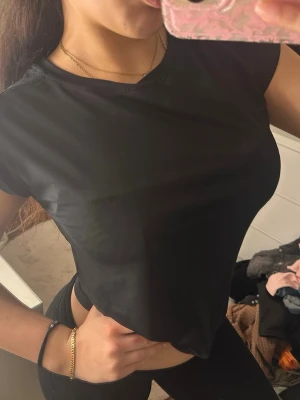 Svart tränings t-shirt - En enkel och stilren svart  t-shirt med korta ärmar. Perfekt till jeans eller kjol för en clean look. T-shirten har en rund halsringning och sitter tight mot kroppen.