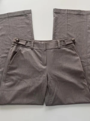 Vida grå kostymbyxor - Snygga grå kostymbyxor med vid passform och fina detaljer. Passar mig bra som är 177cm💕 Skriv bara vid frågor! Midjemått:43 Innerbenslängd:80