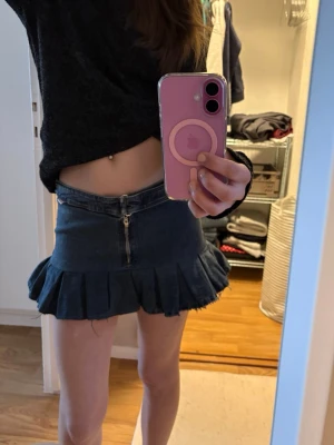 Mörkblå jeanskjol med volangkant - Mörkblå jeanskjol från miss sixty med volangkant och rå kant nedtill. Kjolen har dragkedja framtill, ficka på rumpan och spänne i midjan