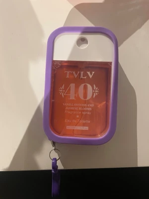TVLV 40 Vanillawoods & Jasmine Blooms - Parfymen doftar söt och blommig doft. Flaskan är rektangulär med lila silikonfodral och nyckelring, och rymmer 48 ml. Aldrig använd. Den doftar så gott 