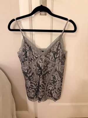 Spetslinne - Jättesnygg topp som passar perfekt till fest eller finare tillfällen. I silver med mönster 