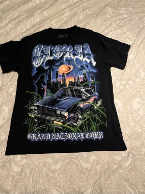 Svart Kendrick Lamar tour t-shirt - Svart t-shirt med  tryck fram och bak från Kendrick Lamars Grand National Tour. Köpt 2025 och använd en gång, därför är den som nyskick! (10/10). Materialet är 100% bomull. Passformen är normal