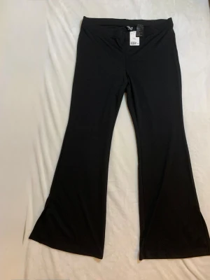 Svarta bootcut leggings från HM - Säljer ett par svarta leggings från HM med bootcut-modell. De har hög midja och är tillverkade i ett stretchigt, mjukt material som sitter skönt. Perfekta för dig som gillar en enkel men trendig look.