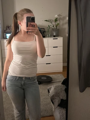 Vit linnetopp med smala axelband - Säljer ett stilrent vitt linne med smala axelband och rak halsringning. Perfekt att matcha med jeans eller kjol. Linnet är i mjukt material, vilket gör det bekvämt och lätt att bära. Säljer pårgrund av att jag inte har samma storlek längre. OBS! Linnet är från h&m barn avdelning, där storleken är 14y+ vilket innebär 170. Storlek 34-36.